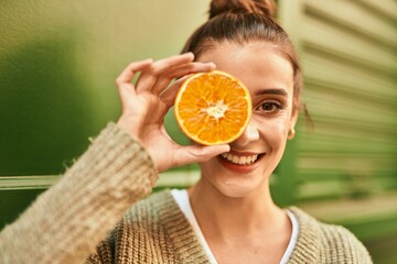 Wall Mural - Beautiful brunette woman smiling happy with half orange over eye