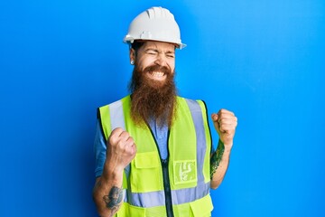 Poster - Redhead man with long beard wearing safety helmet and reflective jacket excited for success with arms raised and eyes closed celebrating victory smiling. winner concept.