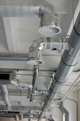 Air flow and ventilation system on the ceiling of large buildings. Ventilation pipes in silver insulation material hanging from the ceiling inside new building.