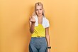 Beautiful blonde sports woman wearing workout outfit showing middle finger, impolite and rude fuck off expression