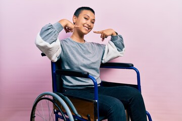 Poster - Beautiful hispanic woman with short hair sitting on wheelchair smiling cheerful showing and pointing with fingers teeth and mouth. dental health concept.