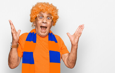 Senior hispanic man football hooligan cheering game celebrating victory with happy smile and winner expression with raised hands