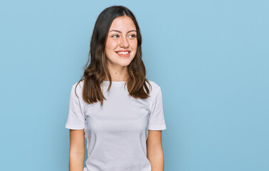 Young beautiful woman wearing casual white t shirt looking away to side with smile on face, natural expression. laughing confident.