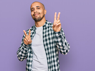 Wall Mural - Hispanic adult man wearing casual clothes smiling looking to the camera showing fingers doing victory sign. number two.