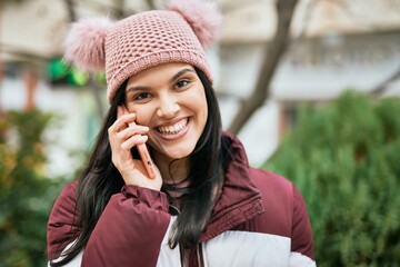 Young hispanic girl smiling happy talking on the smartphone at the city.