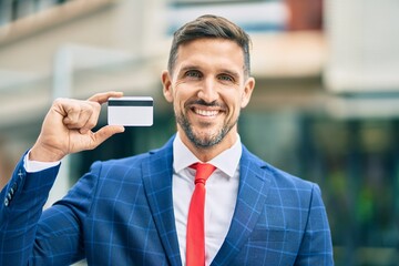 Wall Mural - Young caucasian businessman smiling happy holding credit card at the city.