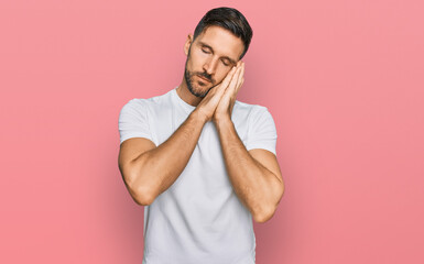 Wall Mural - Handsome man with beard wearing casual white t shirt sleeping tired dreaming and posing with hands together while smiling with closed eyes.