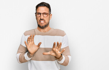 Canvas Print - Handsome man with beard wearing casual clothes and glasses disgusted expression, displeased and fearful doing disgust face because aversion reaction.