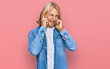 © Krakenimages.com - Caucasian man with blond long hair wearing casual denim jacket covering ears with fingers with annoyed expression for the noise of loud music. deaf concept.