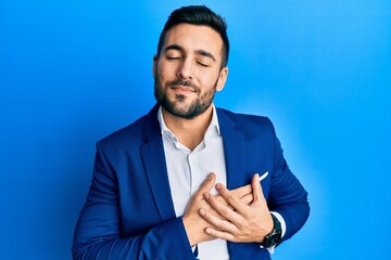 Sticker - Young hispanic businessman wearing business jacket smiling with hands on chest with closed eyes and grateful gesture on face. health concept.