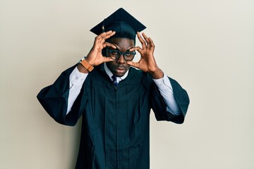 Wall Mural - Handsome black man wearing graduation cap and ceremony robe trying to open eyes with fingers, sleepy and tired for morning fatigue