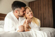 © Dusan Petkovic - A happy and fulfilled woman in the arms of a successful man. Romantic mornings at the hotel. A man and a woman in white robes and on white sheets lie and hug the warm hotel rooms. Love memories