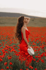 Wall Mural - beautiful woman with dark hair in elegant red dress posing in blooming poppy field