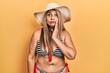 Middle age hispanic woman wearing bikini and summer hat touching mouth with hand with painful expression because of toothache or dental illness on teeth. dentist