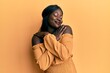 African young woman wearing casual clothes hugging oneself happy and positive, smiling confident. self love and self care