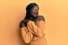 African Young Woman Wearing Casual Clothes Hugging Oneself Happy And Positive, Smiling Confident. Self Love And Self Care