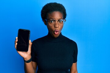 Canvas Print - Young african american girl holding 5g technology smartphone scared and amazed with open mouth for surprise, disbelief face