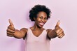 © Krakenimages.com - Young african american woman wearing casual sleeveless t shirt approving doing positive gesture with hand, thumbs up smiling and happy for success. winner gesture.