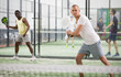 © JackF - Portrait of focused padel player hitting two handed backhand during friendly match in close court