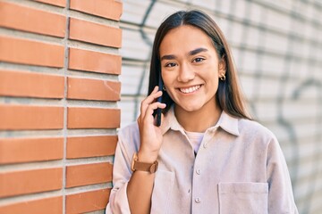 Canvas Print - Young latin girl smiling happy talking on the smartphone at the city.