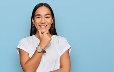 Wall Mural - Young asian woman wearing casual white t shirt looking confident at the camera smiling with crossed arms and hand raised on chin. thinking positive.