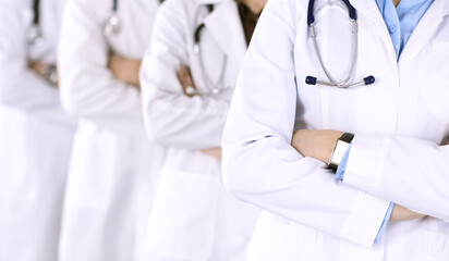 Group of modern doctors standing as a team with arms crossed in hospital office. Medical help, insurance in health care, best desease treatment and medicine concept