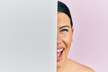 Poster - Beautiful brunette woman holding blank empty banner covering half face smiling and laughing hard out loud because funny crazy joke.