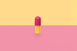 Close-up one colorful powder soft capsule pill on pink yellow background. medicine supplement