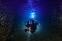 A Male Scuba Diver In The Ocean At Night. The Shot Is Backlit To Create An Interesting Effect