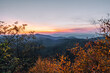 A small break in the color fall foliage reveals the blue layers of the Blue Ridge Mountains during a gorgeous pink, yellow, orange sunrise in Shenandoah National Park, Virginia, USA.