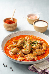 Wall Mural - Chicken stew with paprika, onion and sour cream in plate on concrete background. Traditional Hungarian dish Paprikash.