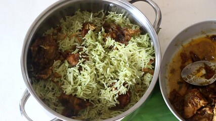 Sticker - Serving boneless chicken curry and rice layer by layer on to a big bowl to prepare chicken biryani