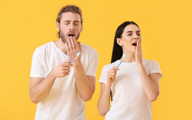 Poster - Tired young couple brushing teeth on color background