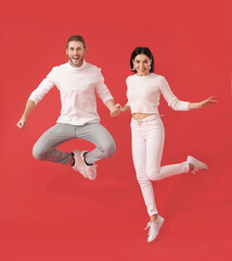 Wall Mural - Happy young couple jumping on color background