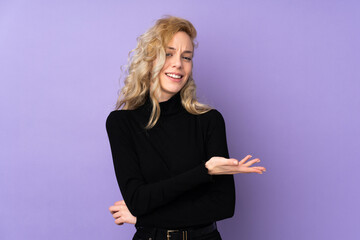 Poster - Young blonde woman isolated on purple background presenting an idea while looking smiling towards