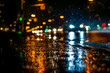 Rainy night in the big city, the cars rides on the road. The view from the sidewalk level