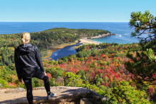 Female Hiker Standing On Ledge Enjoying View Of Water From Beehive Trail In Acadia National Park