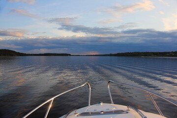 Wall Mural - Russian beautiful evening river landscape front view on the calm water from yacht bow deck with railings at Summer with dark blue cloudy sky on horizon