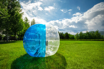 Zorbing Balloon on the summer lawn. inflatable zorb ball outdoor. Leisure activity concept with copy space