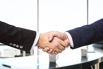 Handshake of two businessmen on the background of bright conference room, partnership concept, close up