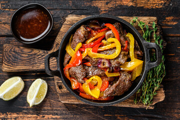 Canvas Print - Fajitas beef meat traditional Mexican food dish in a pan. Dark wooden background. Top view