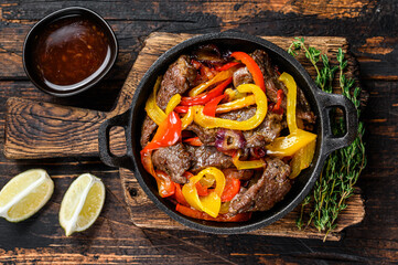 Wall Mural - fajitas beef meat traditional mexican food dish in a pan. dark wooden background. top view