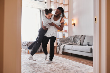 Wall Mural - Father having fun and teaching his teenage kid to dance in modern living room at home