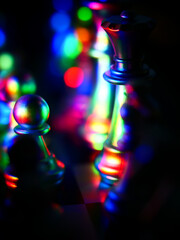 Sticker - Vertical shot of chess pieces on a board illuminated with colorful bokeh lights