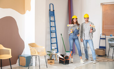 Happy couple with paint rollers in their new house