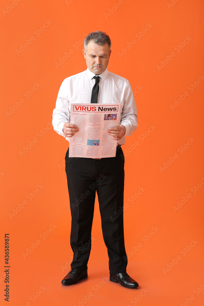 Mature businessman with newspaper on color background