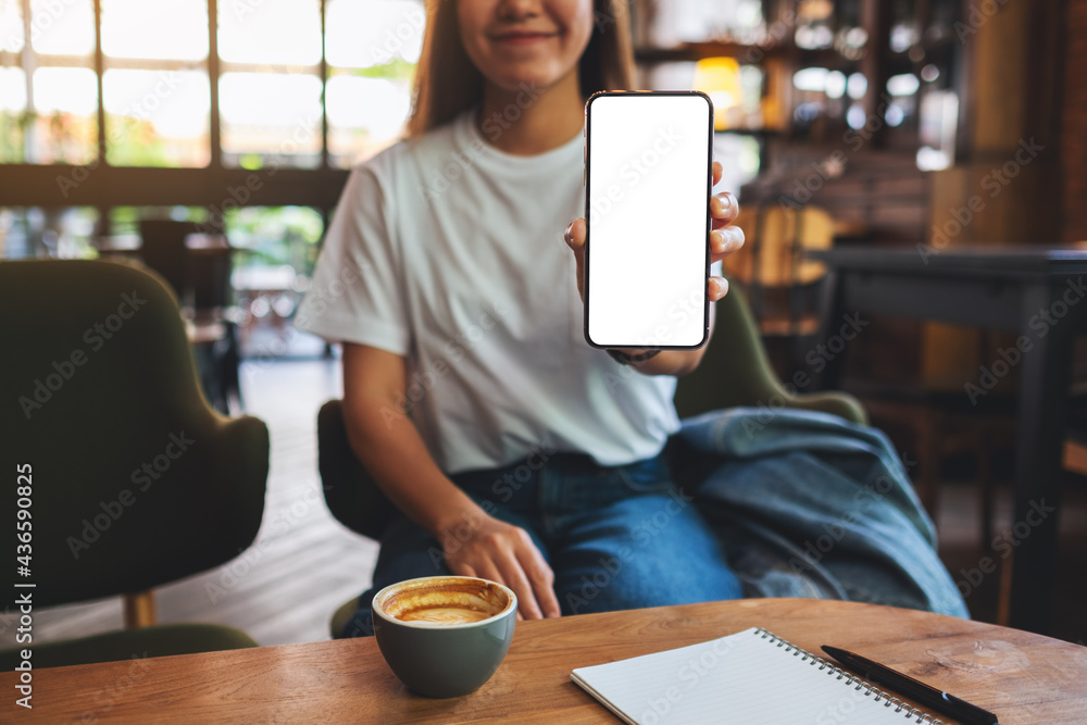 Mockup image of a beautiful woman showing a mobile phone with blank white screen - obrazy, fototapety, plakaty 