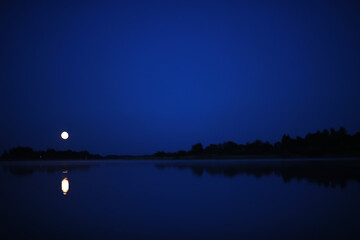 Beautiful colour night sky river. Bright moon. Clouds and stars in high mountains.