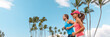 © Maridav - Athlete sport runners couple running landscape banner. Fitness people couple jogging together in summer park outdoor. Horizontal palm trees background. Asian girl, Caucasian friend man.