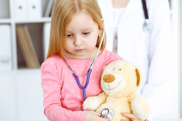 Happy smiling female kid-patient at usual medical inspection. Doctor and young girl in the clinic. Medicine, healthcare concepts